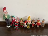 The full collection of ten vinyl faced elves and leprechauns arranged in a row on a dark wood surface.