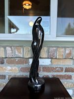 View of the large black glass sculpture from front with natural light showing smooth twisting form and details