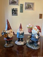 Three vintage standing gnome figurines on a table showing all the items included in the set.