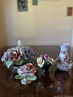Full view of four vintage Capodimonte porcelain floral pieces on brown surface