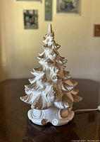 Front view of vintage light-up ceramic Christmas tree on decorative base with gold accents.