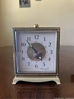 Front view of vintage Westclox Musical Drowse alarm clock showing square dial with beaded border and ornate hands.