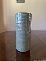 Cylindrical ribbed vase with green to blue glaze with speckles, shown from the front