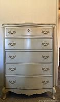 Full view of the white French Provincial tall boy dresser showing five drawers and cabriole legs.