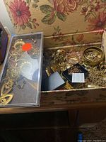 Floral box open with assorted gilt-tone jewelry inside