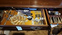 Drawer with assorted serving utensils, tea strainers, and decorative glass leaf plate
