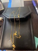 Black jewelry case displaying double-chain Egyptian pendant necklace and two additional chains