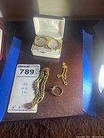All items displayed together on wooden surface: two bracelets, ring, earrings in box.