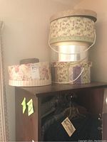 Stack of three floral and patterned vintage-style cardboard hat boxes on top of a wooden cabinet.