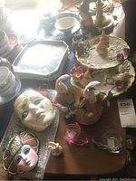 Photo of ceramic masks, Easter bunny candle holders, and witch figurine on display with additional ceramics