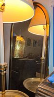 Mirror reflecting nearby lamp and room elements, showing the curved top edge and gold/brass frame.