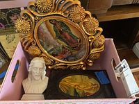 Jesus bust sculpture held to show size, accompanied by Virgin of Guadalupe ornate framed art, and Botticelli's Birth of Venus framed print in box.