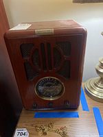 Front view of wooden cabinet radio showing carved front and dial with control knobs