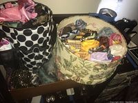 Overall view of containers holding rolled and folded scarves, showing various colors and patterns.