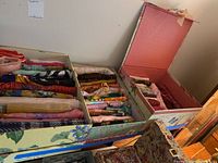 Three decorative boxes filled with neatly folded ladies fashion scarves in multiple colors and patterns.