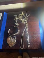 Overall group shot of cuff bracelet, earrings and two necklaces on wooden surface