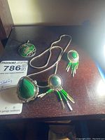 Necklace, earrings, and enamel pendant displayed on wooden surface