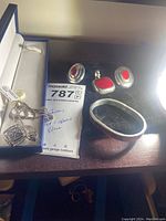 Overview of four jewelry pieces on wooden surface: pendant, earrings, bracelet and necklace in box