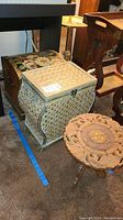 Photo showing the small carved wooden table alongside two decorative storage trunks with woven and carved details.
