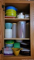 Tall wooden cabinet shelves holding multiple plastic containers of different shapes, colors, and sizes.