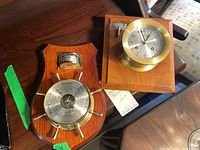 Square wood plaque with Schatz manual clock with brass bezel and winding key placed on top