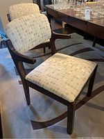 Side angled view of a single dining chair highlighting the dark wood frame and beige geometric circle patterned upholstery on the seat and backrest.
