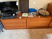 Front view of wood dresser with six drawers, items on top not included