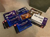 Boxes of assorted golf balls including Wilson ProStaff Senior, Top-Flite Magna, Pinnacle, and Top-Flite XL boxes on carpeted floor.
