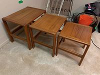 Set of three wooden nesting tables arranged side-by-side showing sizes and wood grain.