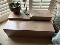 Three painted pedestals arranged near window with labels showing size and lot numbers