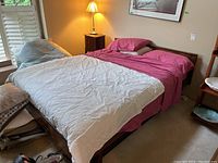 Assembled queen bed frame with mattress, comforter, sheets and stacked pillows