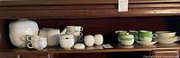 View of entire Rosenthal porcelain china lot showing two distinct patterns arranged on a wooden shelf. Items include teapot, cups, sugar bowls, salt and pepper shakers, plates, creamer, and ice bucket.