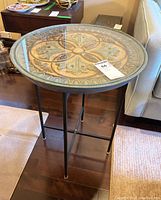 Full view of circular side table showing metal frame and patterned top with glass cover