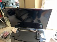 Front view of the Sony TV on metal stand showing the screen, remote, and surrounding area.