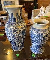 Pair of blue and white ceramic vases with floral motifs; both visible full front view to show design and size difference.