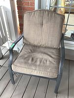 Front view of steel patio chair with beige cushions, showing overall condition.