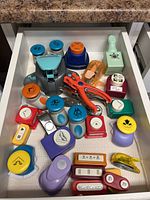 Full drawer view showing all paper punches of various sizes, shapes, and colors.