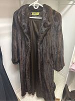 Full view of dark brown mink fur coat hanging.