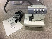 Machine, owner's workbook and foot pedal on carpet