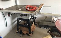 Full view of table saw on metal stand with coiled extension cord on tabletop.