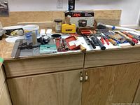 Full view of wooden tool bench with two drawers and collection of assorted hand tools and power tool cases on top.