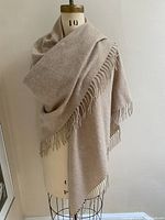 Soft, pale tea color triangular wool shawl displayed draped on a mannequin showing overall size and fringe edges