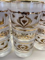 Close-up of the gold leaf floral and foliage design on frosted glass tumbler with gold rim.