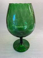 Photo of large green blown glass vessel with scalloped edges and bulbous bowl shape showing overall profile