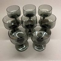 Top view of all 8 smoky grey stemmed aperitif glasses arranged in a group showing size and color consistency.