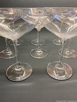 Seven crystal champagne glasses arranged together, showing thin stems and bases.