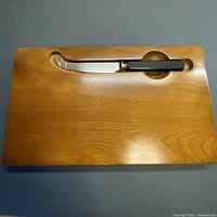 Top view of rectangular wooden cheese board with built-in slot and fitted cheese knife
