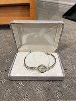 Watch inside original grey velvet box; overhead view of case and bracelet