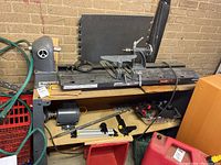 Full view of lathe bed with headstock, tailstock and motor beneath shelf