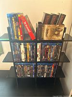 Two-tier shelving unit holding top two rows of DVD/Blu-ray cases and three Lord of the Rings paperbacks on top right